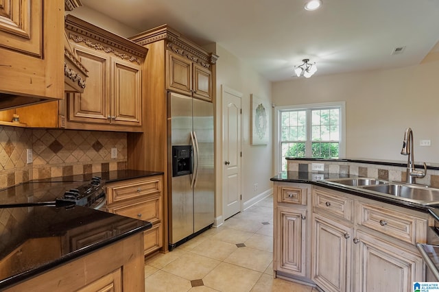 kitchen with dark stone counters, black range oven, light tile patterned floors, sink, and stainless steel built in refrigerator