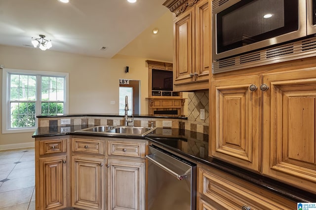 kitchen featuring light tile patterned floors, appliances with stainless steel finishes, sink, kitchen peninsula, and tasteful backsplash