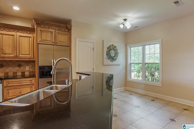 kitchen with backsplash, sink, dark stone counters, light tile patterned flooring, and stainless steel built in refrigerator