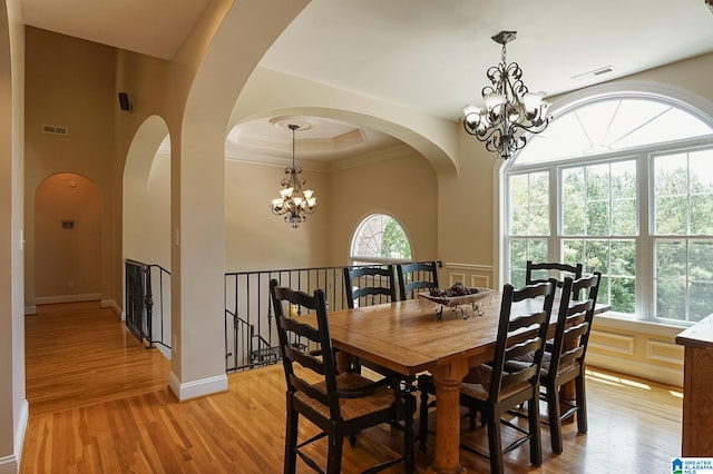 dining space with crown molding, a notable chandelier, and light hardwood / wood-style floors