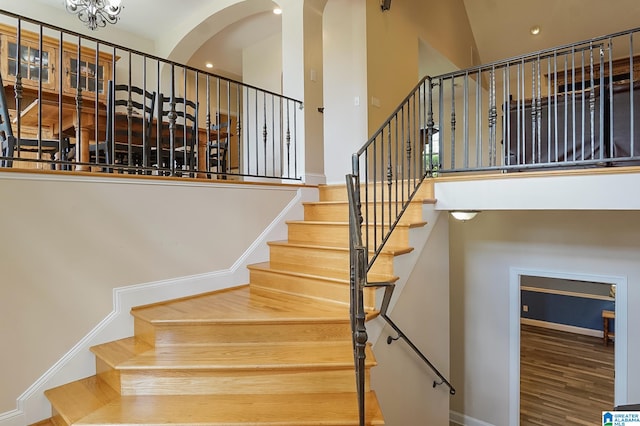 staircase with a towering ceiling and hardwood / wood-style flooring