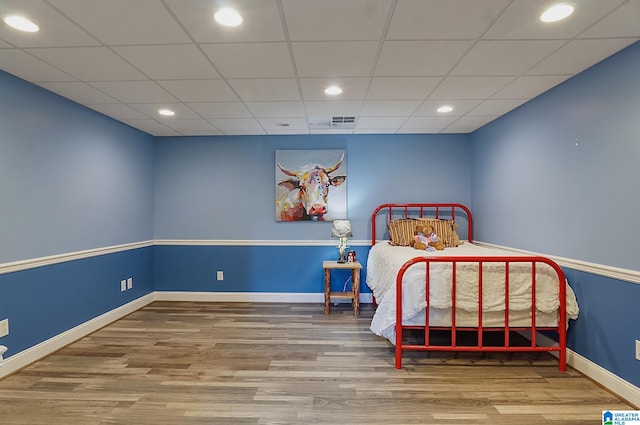 bedroom featuring hardwood / wood-style floors and a drop ceiling