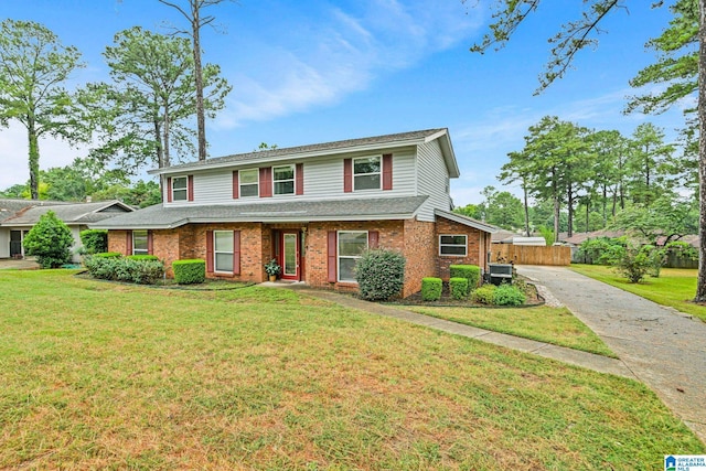 traditional home with a front yard, fence, brick siding, and driveway