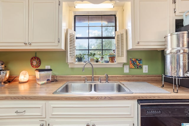 kitchen featuring a sink, light countertops, black dishwasher, and white cabinets