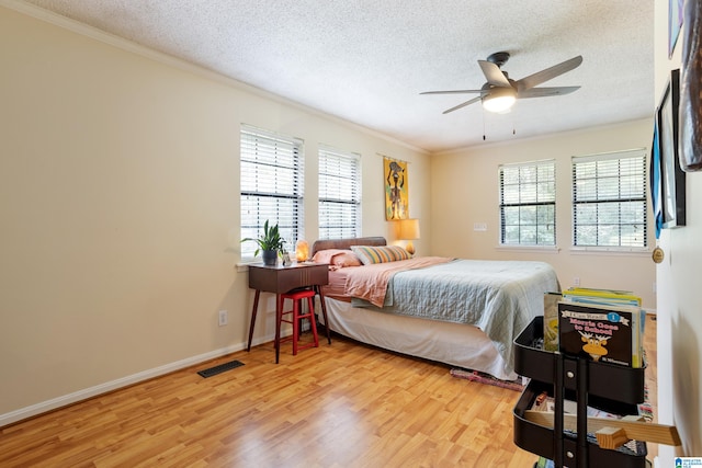 bedroom featuring multiple windows, ornamental molding, ceiling fan, and light hardwood / wood-style flooring