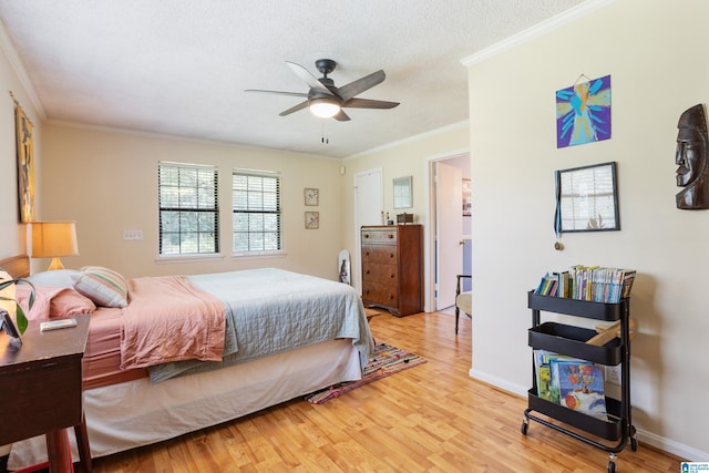 bedroom featuring light wood-style flooring, a textured ceiling, ornamental molding, and a ceiling fan