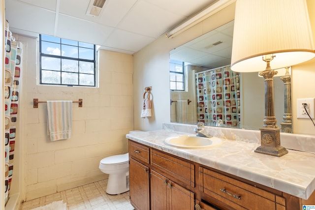 bathroom with a shower with shower curtain, a paneled ceiling, vanity, and toilet