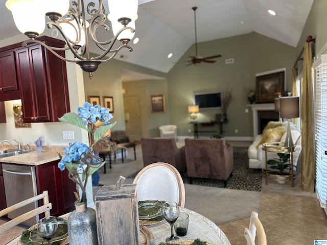 dining room with sink, vaulted ceiling, a fireplace, and ceiling fan with notable chandelier