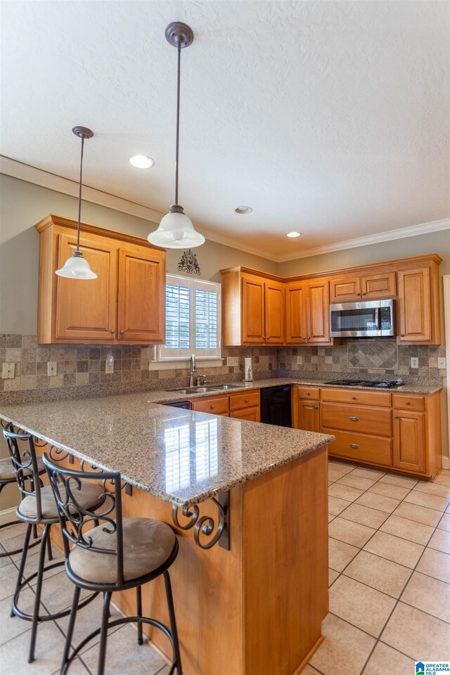 kitchen featuring gas stovetop, hanging light fixtures, kitchen peninsula, ornamental molding, and a breakfast bar