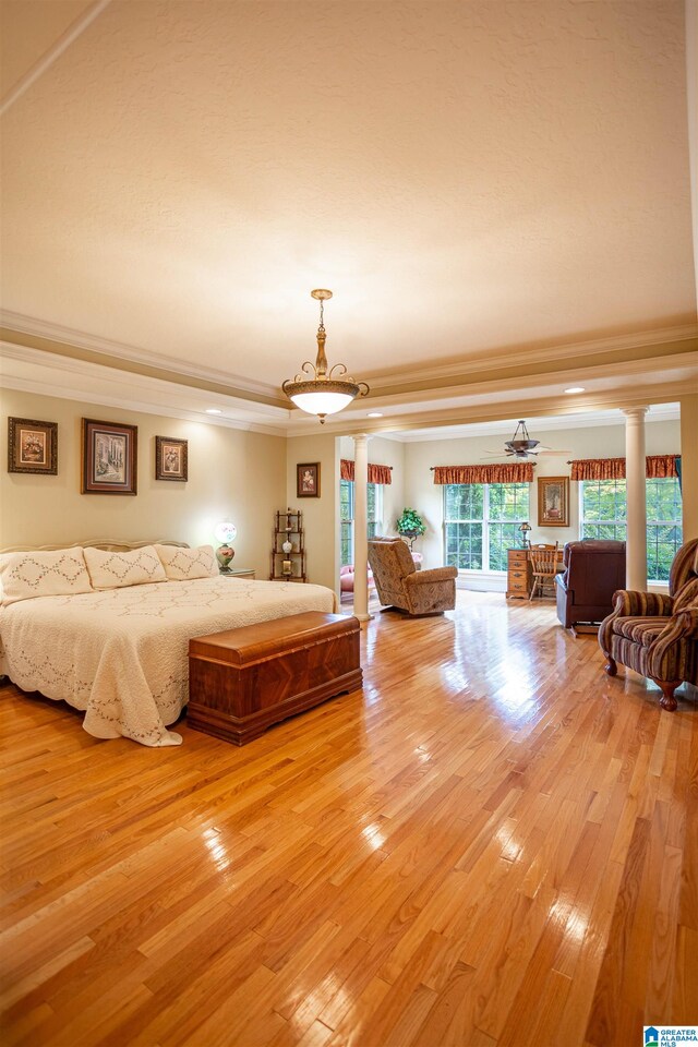 bedroom featuring light hardwood / wood-style flooring, ornamental molding, and ornate columns