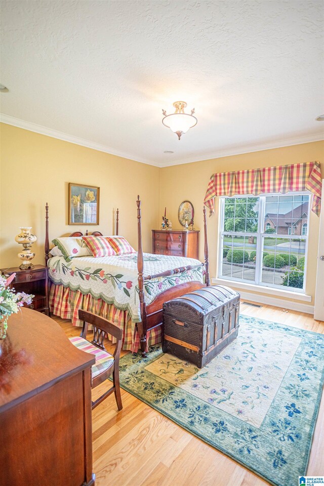 bedroom featuring ornamental molding, a textured ceiling, and hardwood / wood-style floors