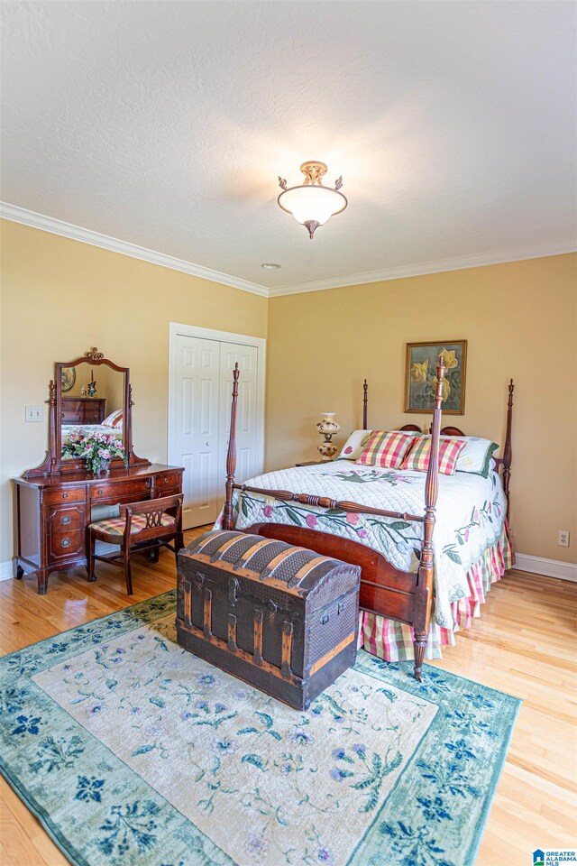 bedroom with crown molding, hardwood / wood-style flooring, and a closet