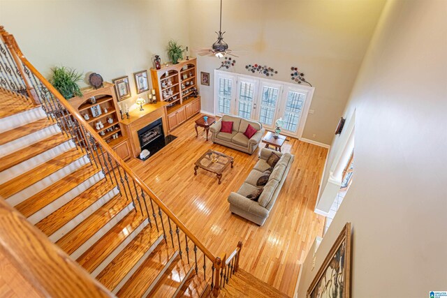 living room featuring light wood-type flooring, a high ceiling, and ceiling fan