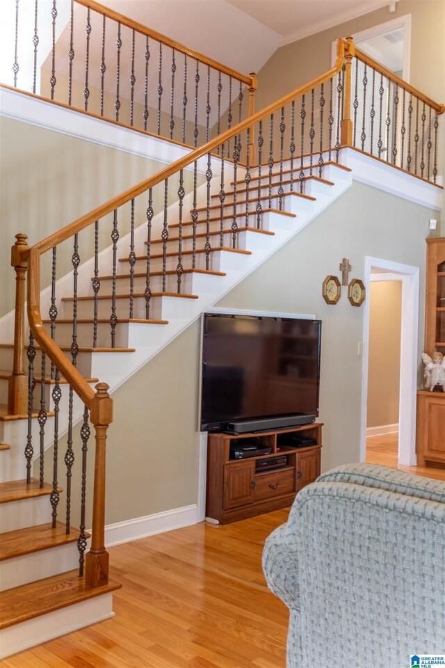 staircase featuring high vaulted ceiling and hardwood / wood-style flooring