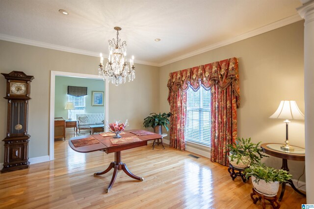 dining space featuring light hardwood / wood-style flooring, ornamental molding, and an inviting chandelier