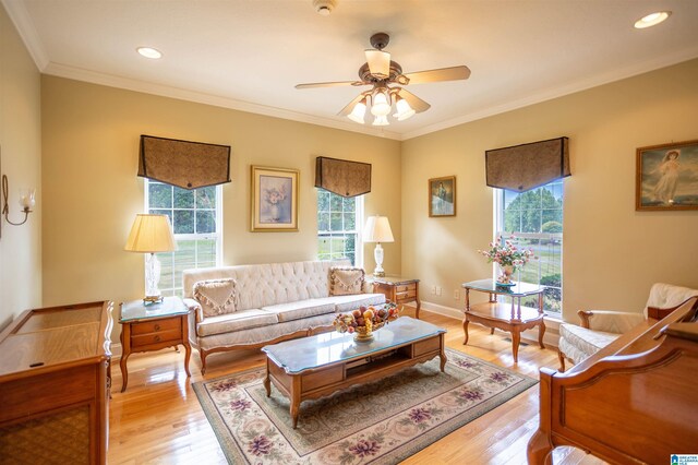 living room featuring light wood-type flooring, ceiling fan, ornamental molding, and a healthy amount of sunlight