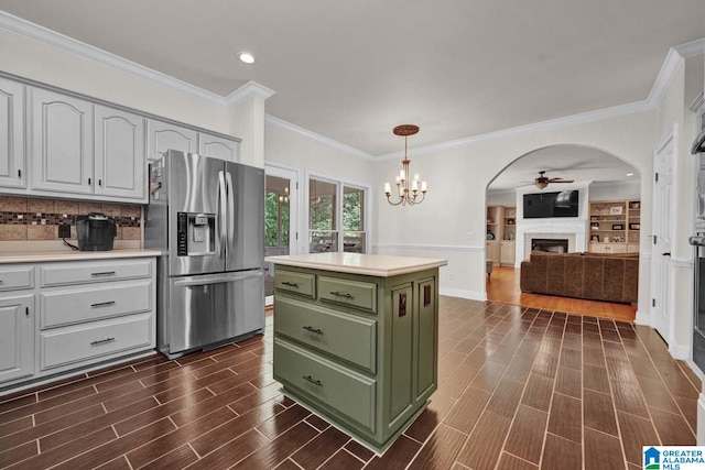 kitchen featuring stainless steel refrigerator with ice dispenser, dark wood-type flooring, ceiling fan with notable chandelier, and a center island