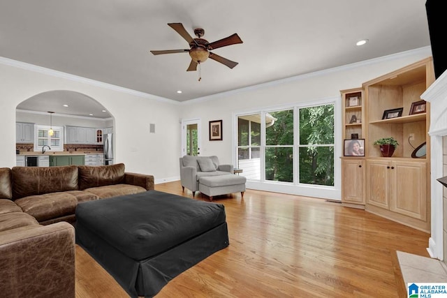 living room featuring light hardwood / wood-style flooring, ceiling fan, and ornamental molding