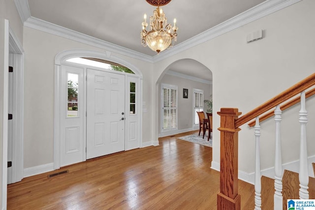 foyer entrance with crown molding, light hardwood / wood-style flooring, and a notable chandelier