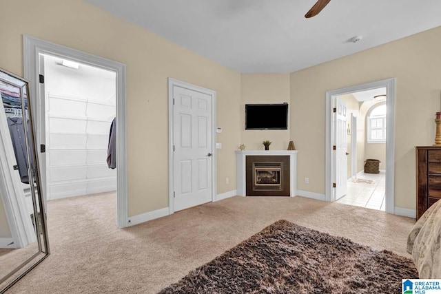 carpeted bedroom featuring a walk in closet, ceiling fan, connected bathroom, and a closet