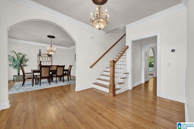 foyer featuring crown molding, wood-type flooring, and a notable chandelier