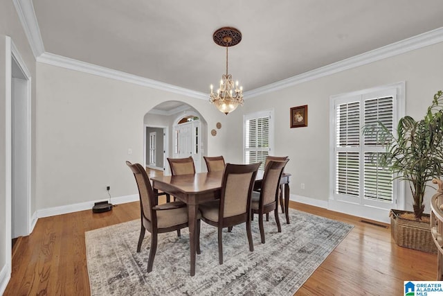 dining space with an inviting chandelier, light hardwood / wood-style floors, and ornamental molding