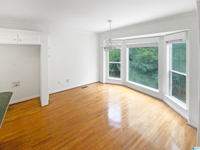 empty room with a notable chandelier and hardwood / wood-style floors