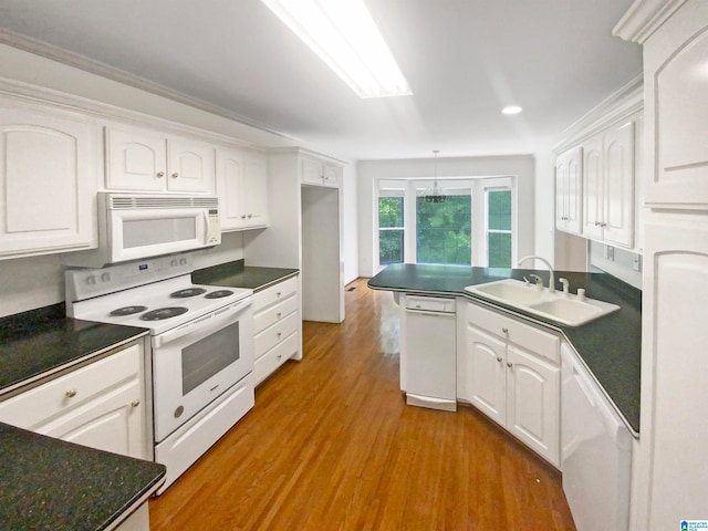 kitchen with hardwood / wood-style floors, white appliances, kitchen peninsula, sink, and white cabinets