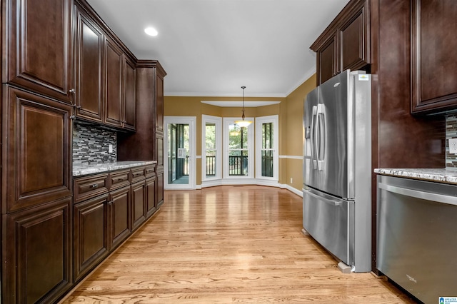 kitchen with light stone counters, stainless steel appliances, light hardwood / wood-style floors, decorative backsplash, and ornamental molding