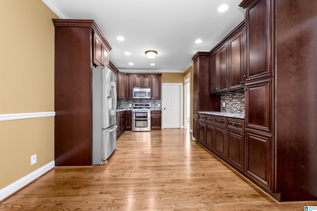 kitchen featuring light wood-type flooring, crown molding, stainless steel appliances, and decorative backsplash