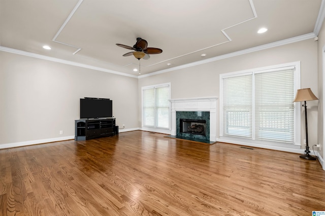 unfurnished living room with ceiling fan, crown molding, a high end fireplace, and light hardwood / wood-style flooring