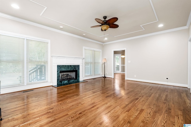 unfurnished living room featuring ceiling fan, hardwood / wood-style flooring, a fireplace, and ornamental molding