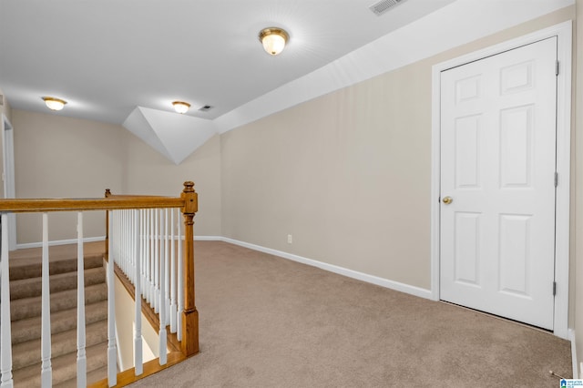 hallway featuring vaulted ceiling and light colored carpet