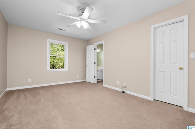 unfurnished bedroom with light colored carpet, connected bathroom, and ceiling fan