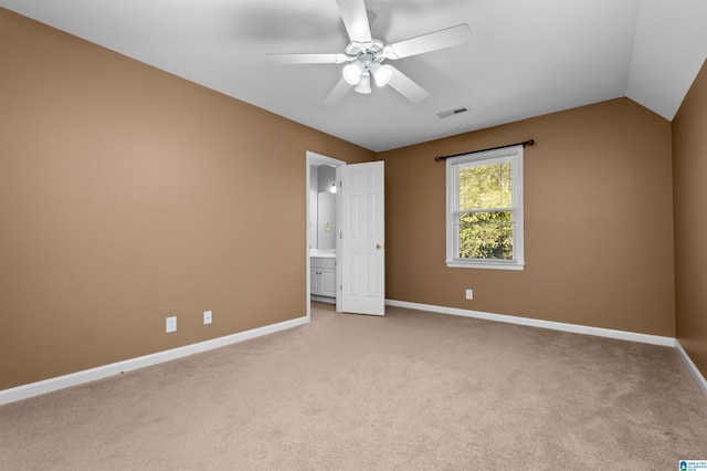 unfurnished bedroom featuring light colored carpet, lofted ceiling, ensuite bathroom, and ceiling fan