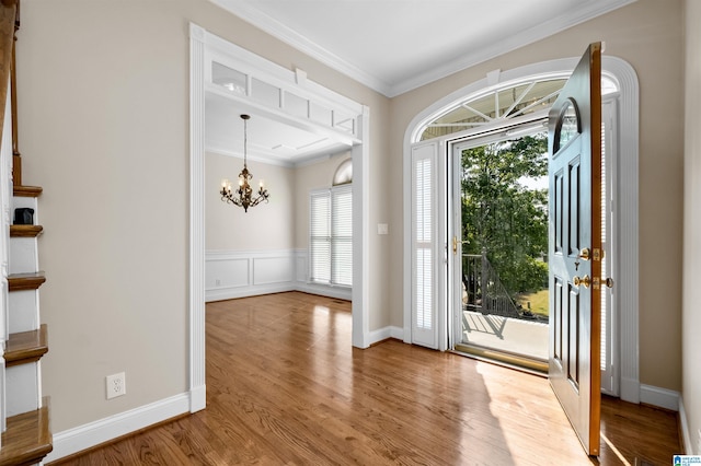 entryway featuring ornamental molding, hardwood / wood-style flooring, and an inviting chandelier