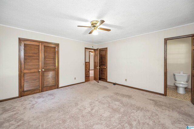 unfurnished bedroom with light colored carpet, a textured ceiling, connected bathroom, and ceiling fan