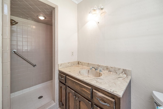 bathroom with vanity, toilet, and tiled shower