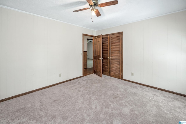 unfurnished bedroom featuring a closet, ceiling fan, carpet, and ornamental molding