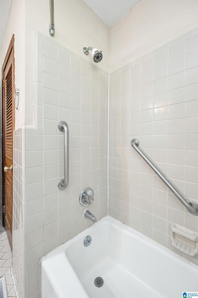 bathroom with tiled shower / bath and a textured ceiling