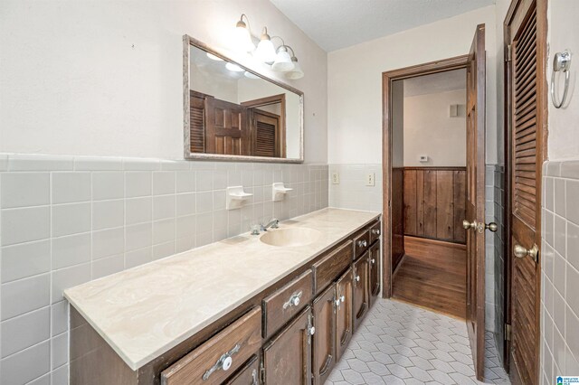 bathroom featuring a textured ceiling, vanity, backsplash, tile walls, and tile patterned floors