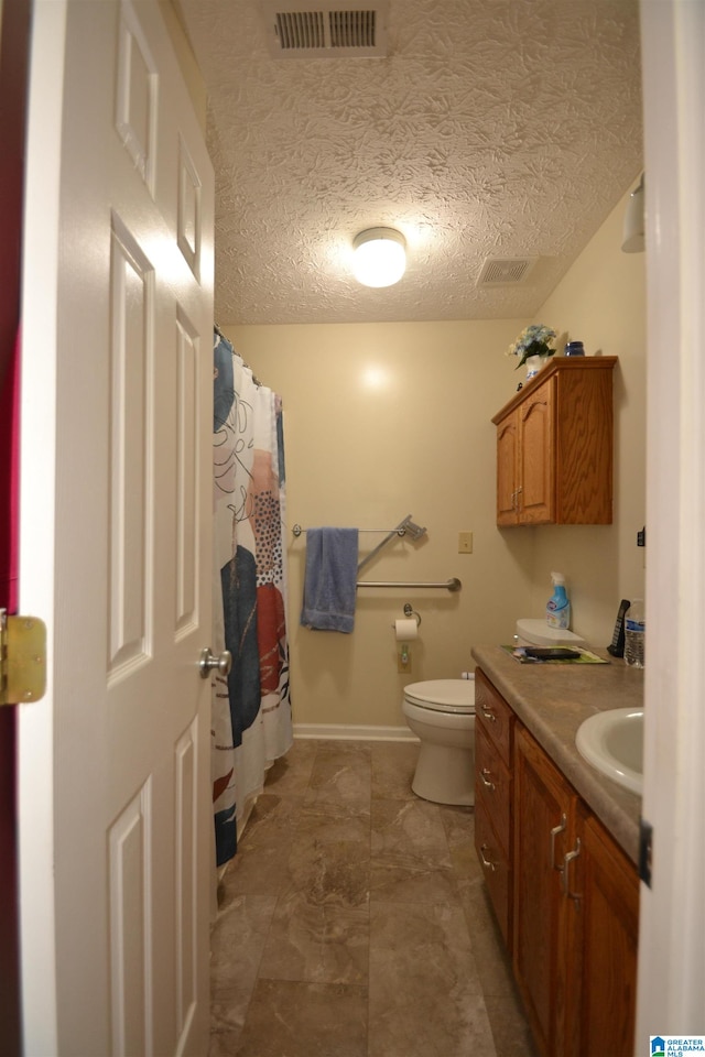 bathroom with vanity, toilet, and a textured ceiling