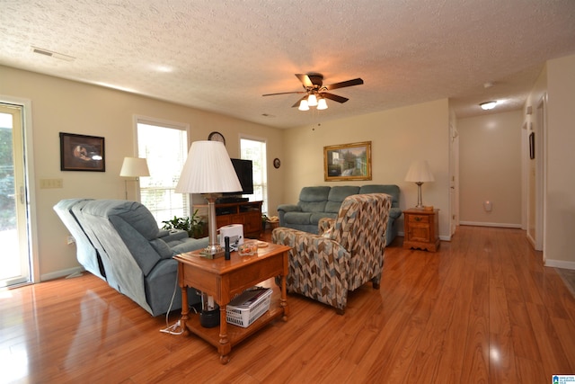 living room with a textured ceiling, ceiling fan, and hardwood / wood-style flooring