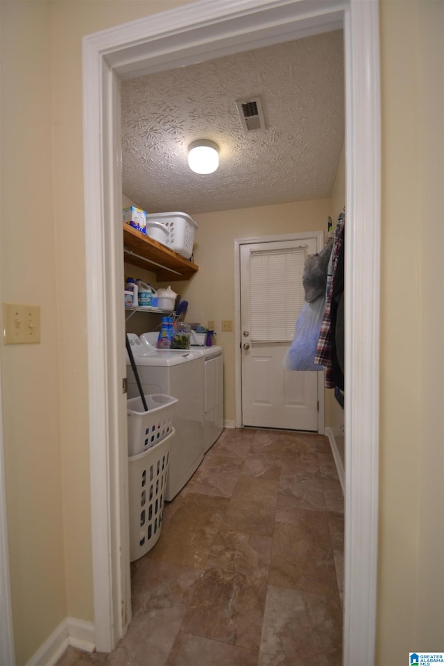 washroom with a textured ceiling and washer and clothes dryer