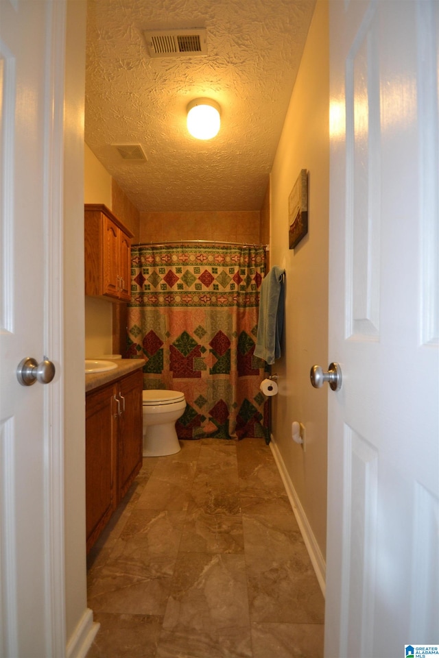 bathroom featuring vanity, toilet, and a textured ceiling