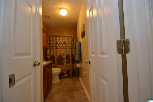 bathroom with vanity, toilet, a shower with shower curtain, and a textured ceiling