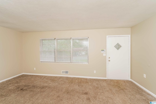 unfurnished room featuring light carpet and a textured ceiling