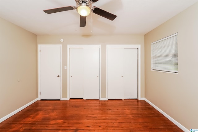 unfurnished bedroom with ceiling fan, two closets, and hardwood / wood-style flooring