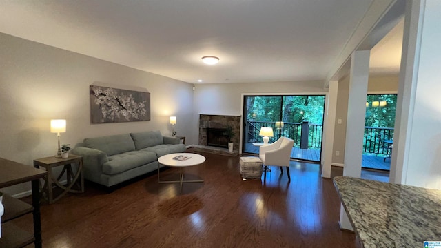 living room with dark wood-type flooring and a stone fireplace