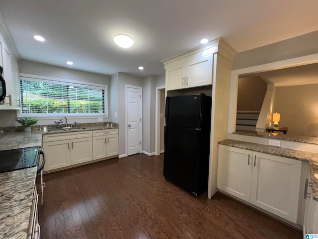 kitchen featuring dark wood-type flooring, white cabinetry, black refrigerator, and sink